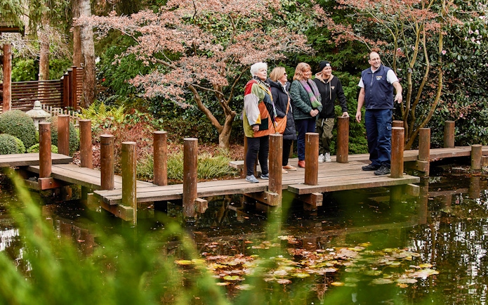 Group on a wooden bridge in a garden during Hobart city tour.