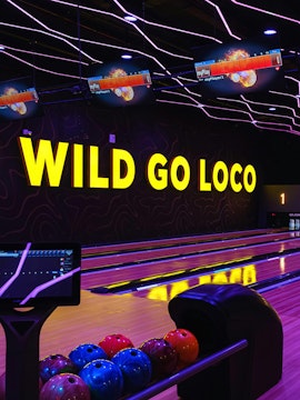 Bowling alley with neon lights and colorful balls in Dubai theme park.