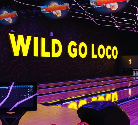 Bowling alley with neon lights and colorful balls in Dubai theme park.