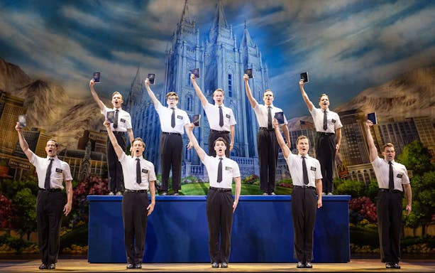 Cast performing The Book of Mormon on stage in Sydney with a backdrop of a temple.