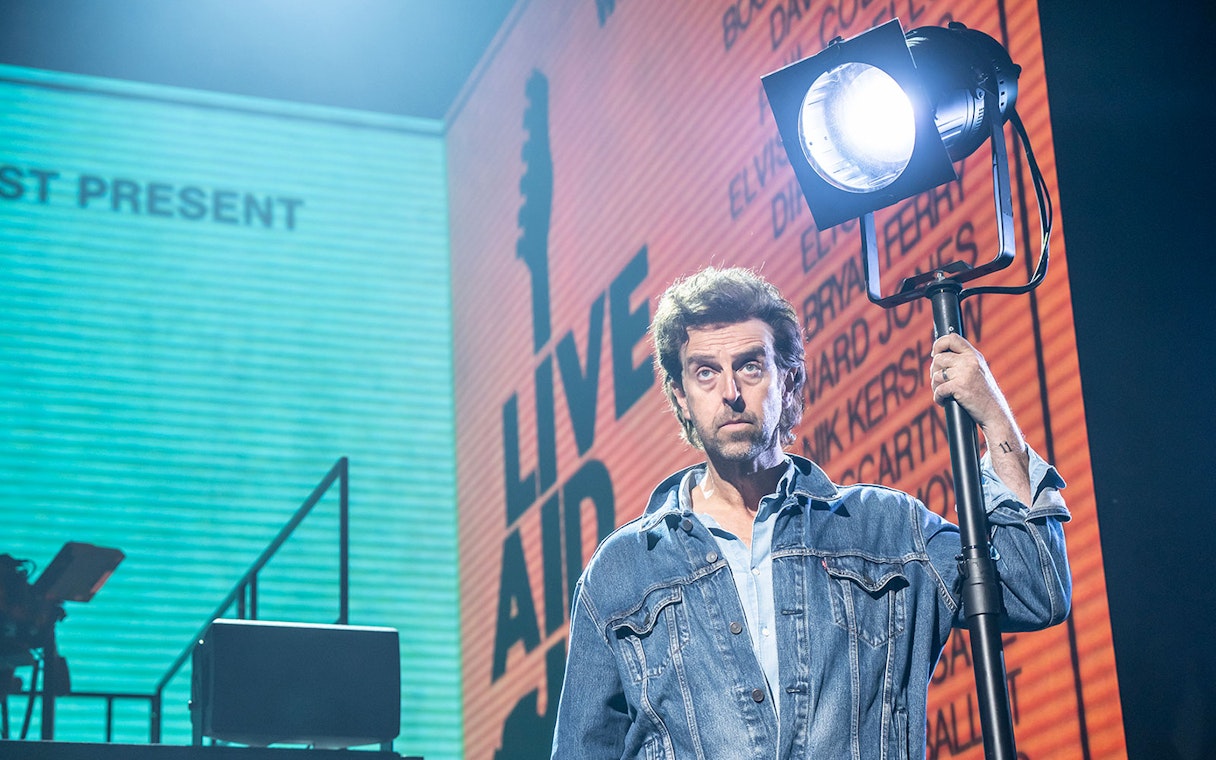 Performer holding a spotlight on stage at Just for One Day event.