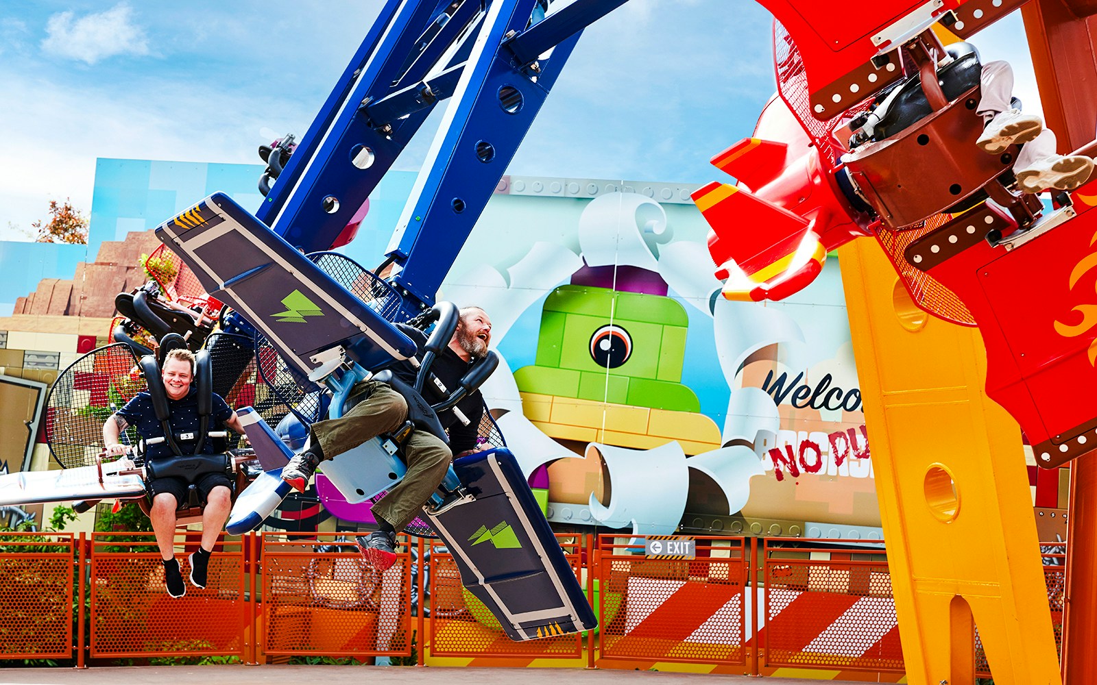 Visitors enjoying a ride at LEGOLAND Billund with colorful LEGO-themed backdrop.