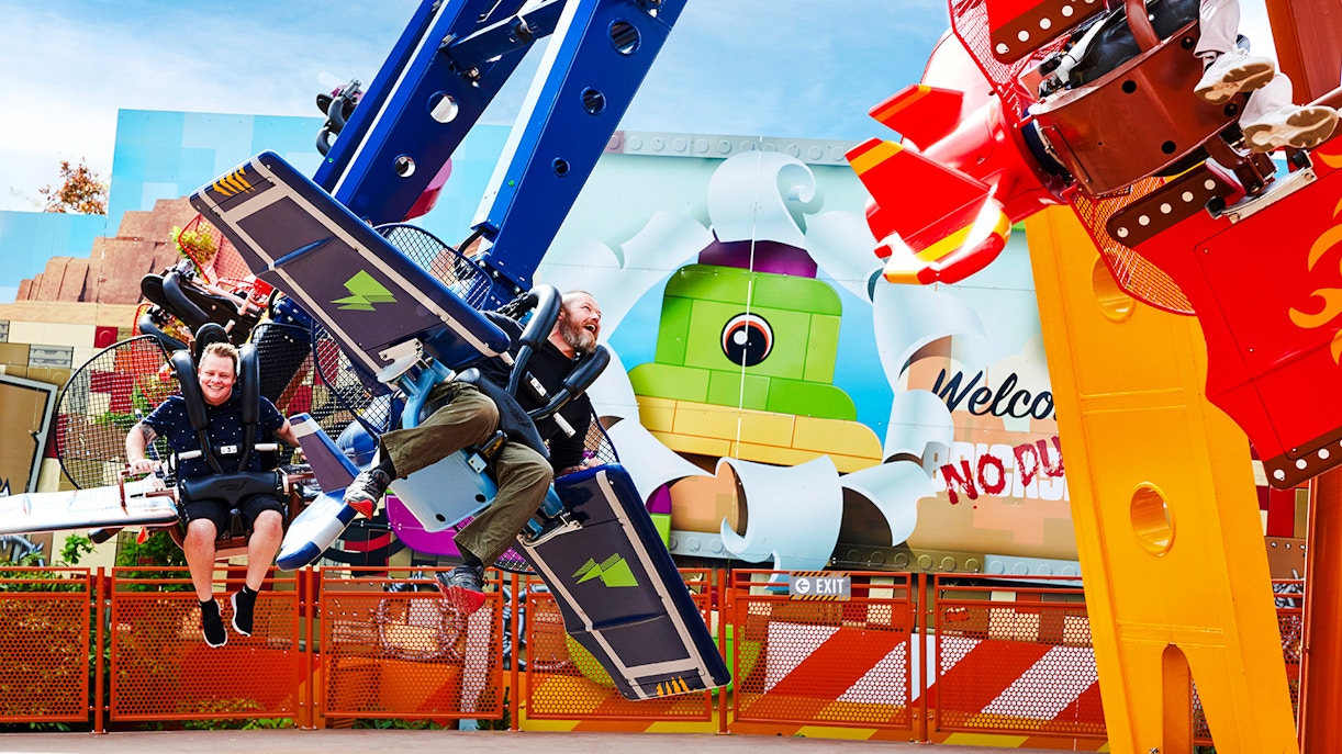 Visitors enjoying a ride at LEGOLAND Billund with colorful LEGO-themed backdrop.