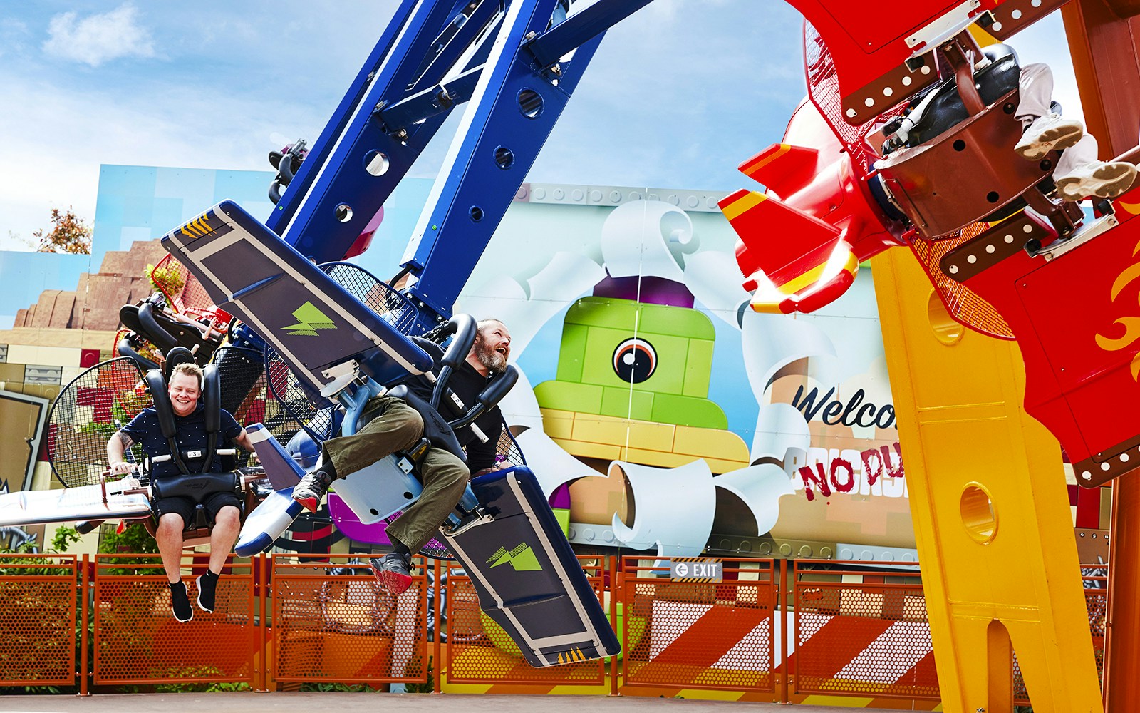 Visitors enjoying a ride at LEGOLAND Billund with colorful LEGO-themed backdrop.