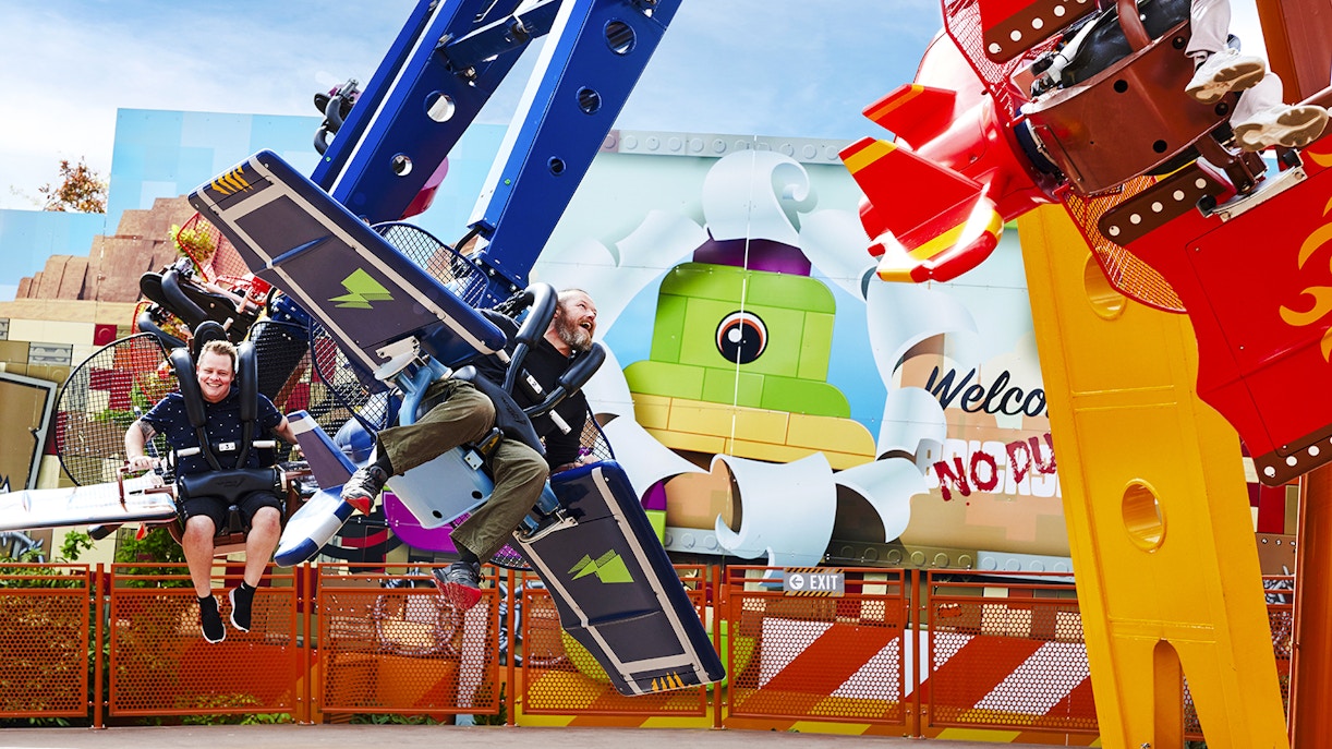 Visitors enjoying a ride at LEGOLAND Billund with colorful LEGO-themed backdrop.