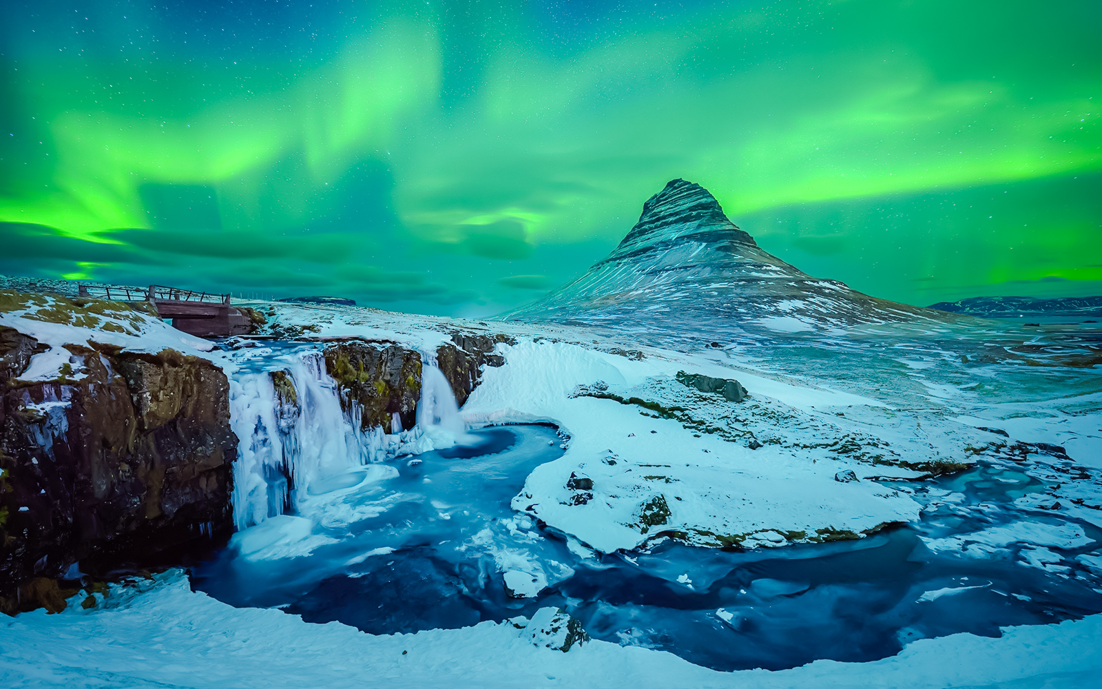 Kirkjufell mountain with Northern Lights in Reykjavik, Iceland, over snowy landscape and waterfall.