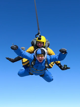 Tandem skydiving over clear blue sky, global adventure experience.