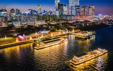 Han River night cruise with illuminated boats and Seoul skyline in the background.
