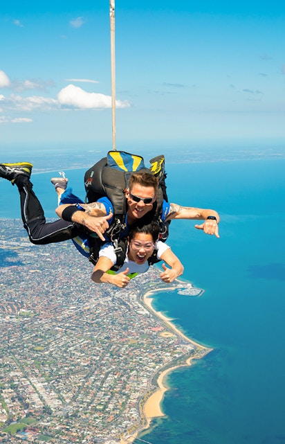 Tandem skydivers over St Kilda Beach, Melbourne with coastline view.
