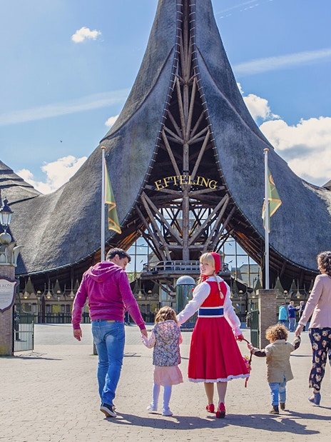 Family walking towards Efteling Theme Park entrance with iconic spire architecture.