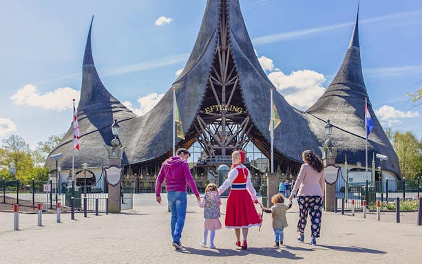 Family walking towards Efteling Theme Park entrance with iconic spire architecture.