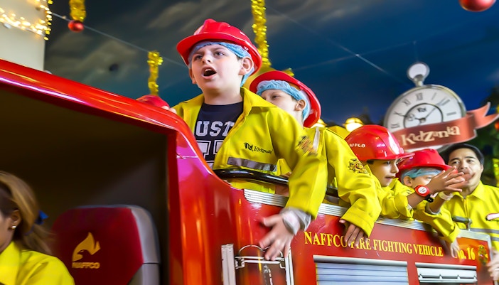 Children engaging fire fighter role-play activities at KidZania Abu Dhabi indoor theme park.
