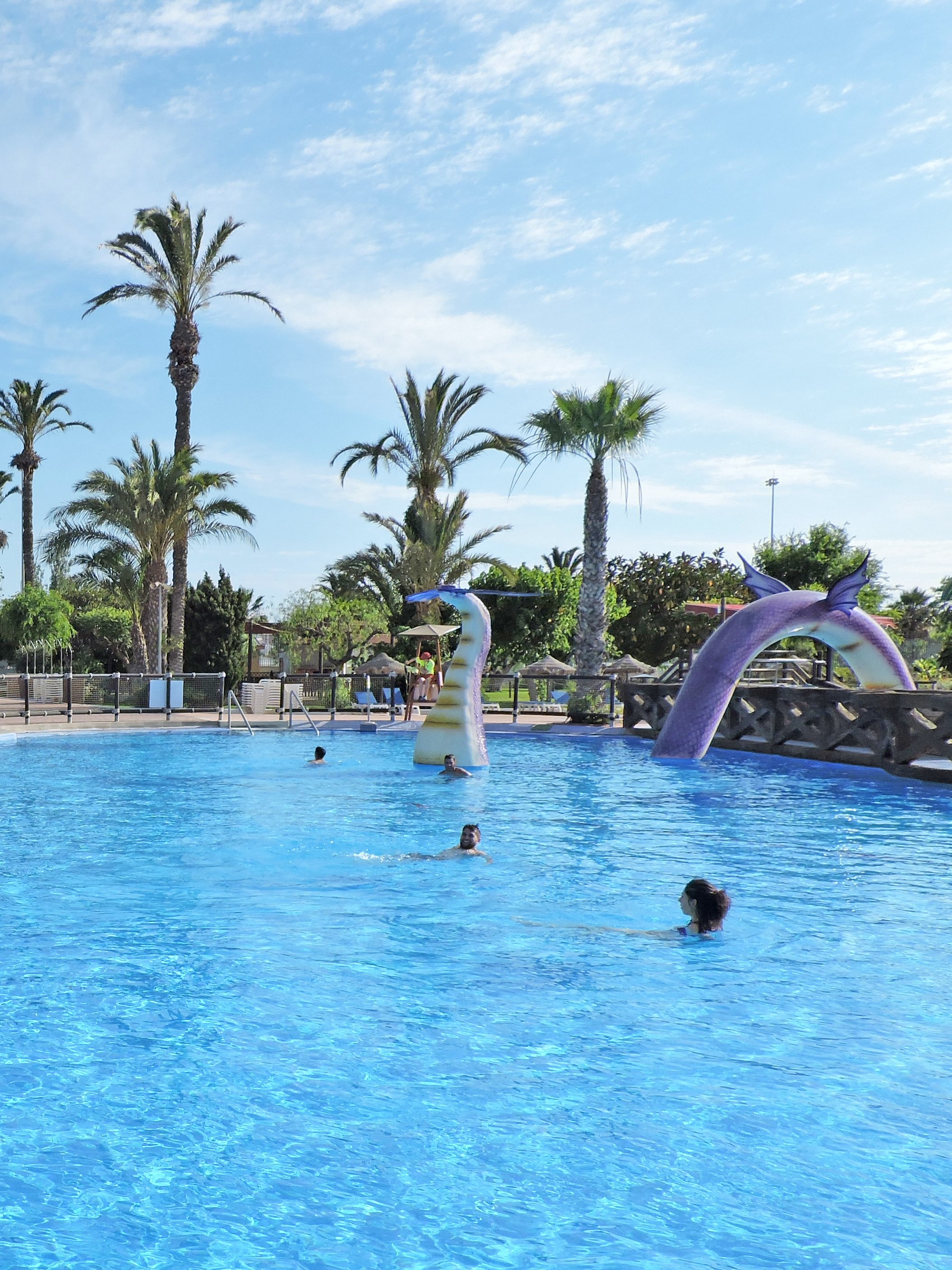 People swimming in a pool with a dragon slide at Aqualand Torremolinos.