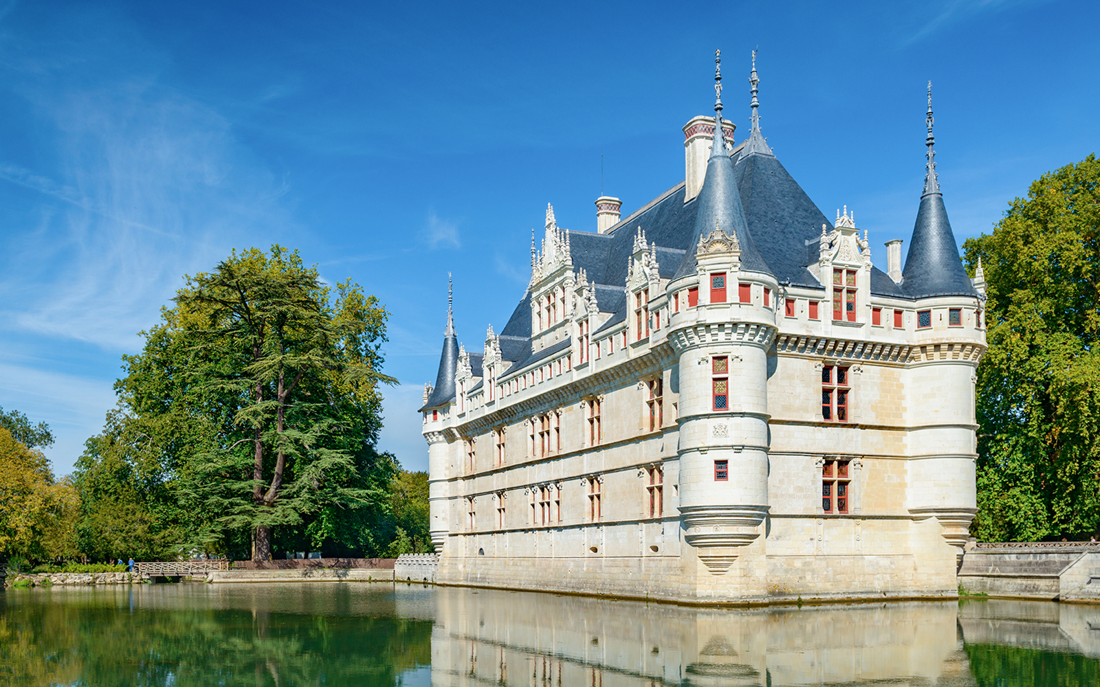 Château d'Azay-le-Rideau reflecting in a calm moat, surrounded by lush trees.