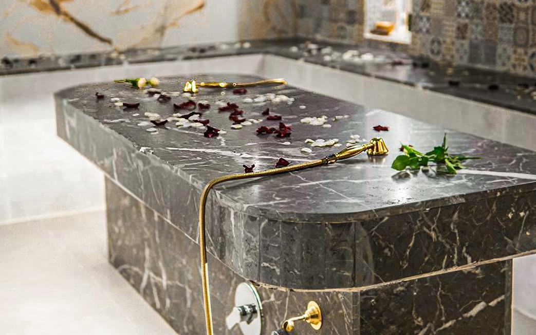 Hammam spa table with rose petals and gold shower head.