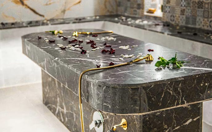 Hammam spa table with rose petals and gold shower head.