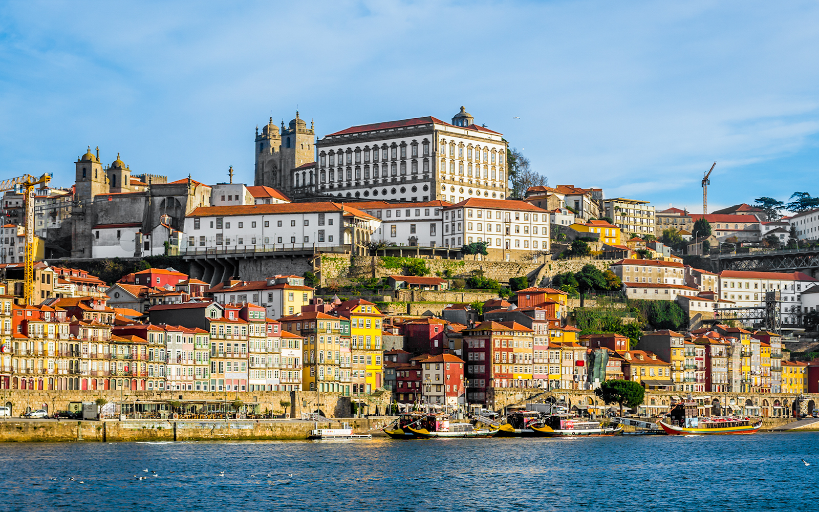 Porto cityscape with colorful buildings and bishop’s palace viewed from Douro River.
