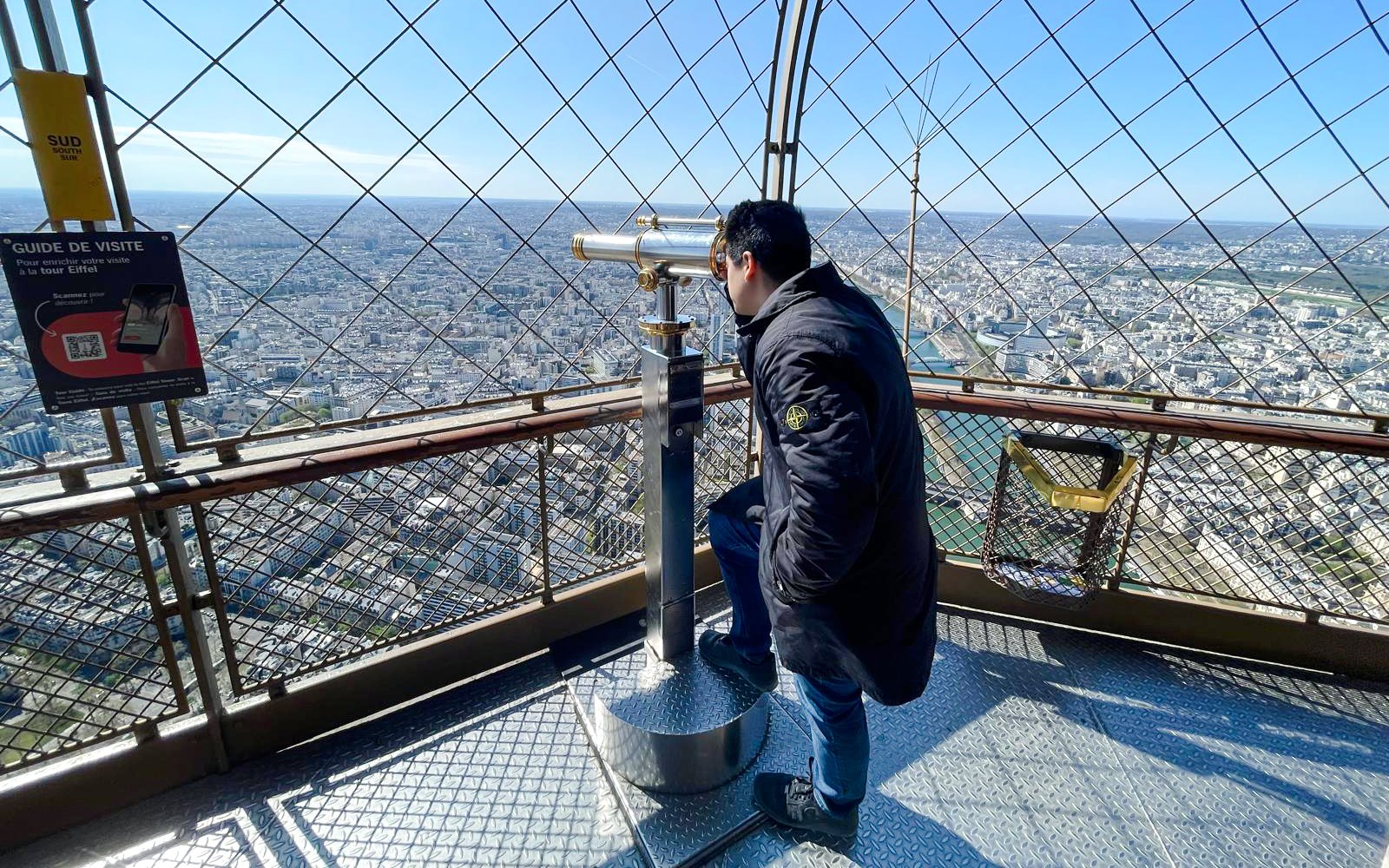 Person using telescope on Eiffel Tower observation deck, Paris, France.
