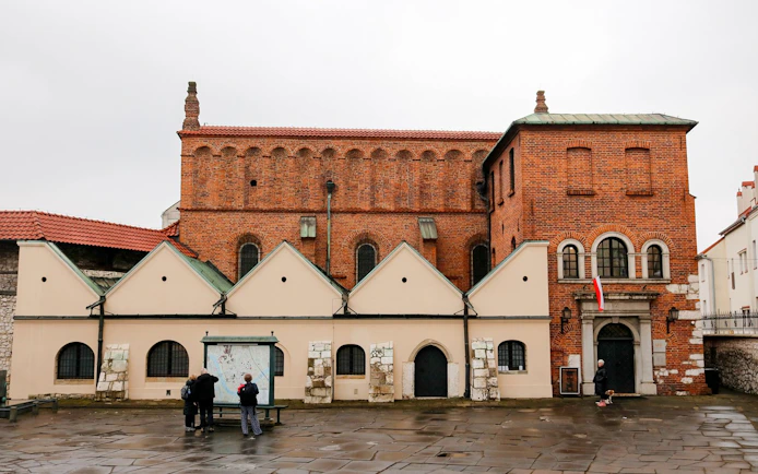 Exterior of Old Synagogue in Jewish Ghetto, Krakow, Poland with visitors reading a map.