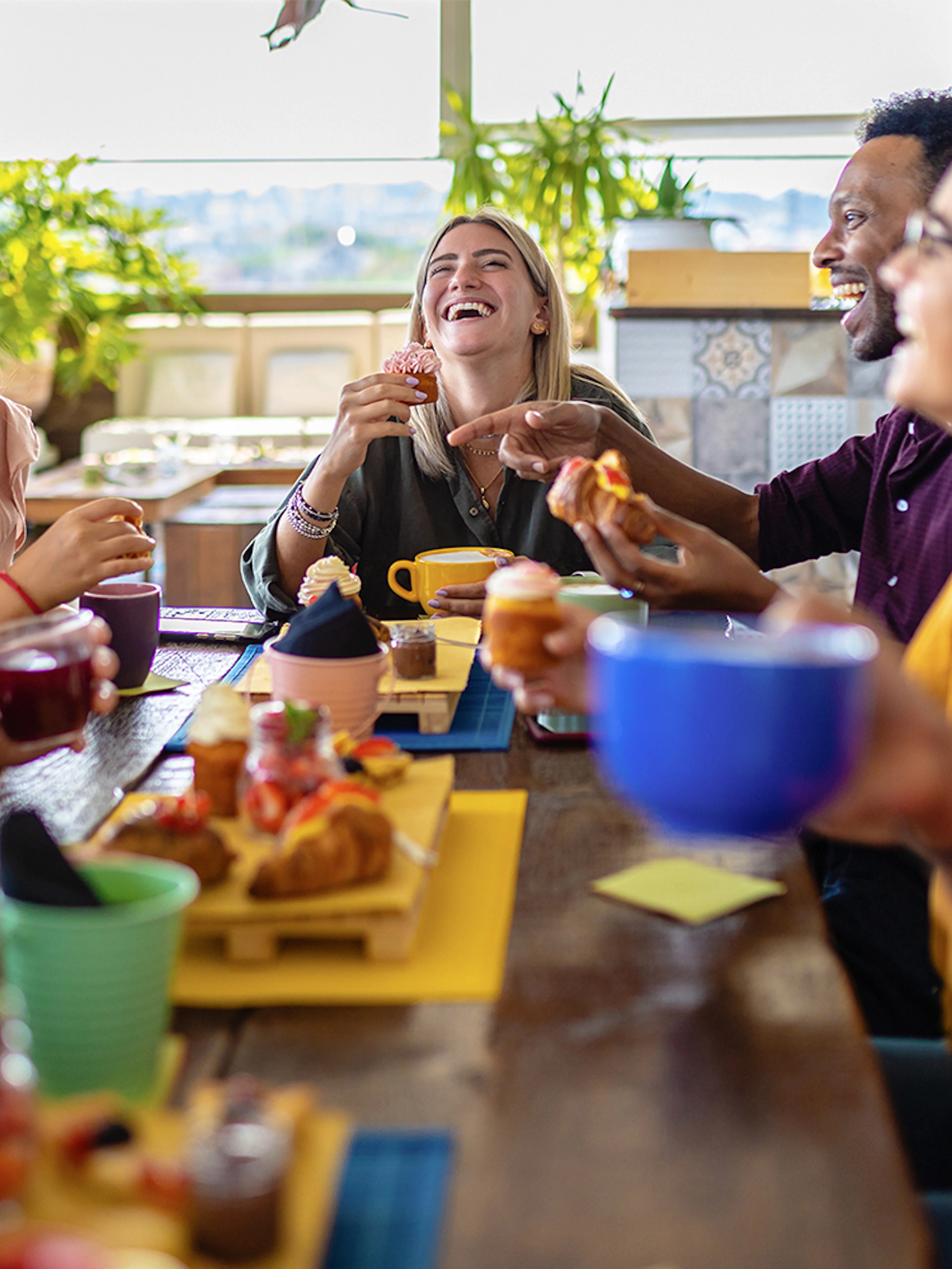 Group of friends enjoying lunch together at a table with drinks and pastries.