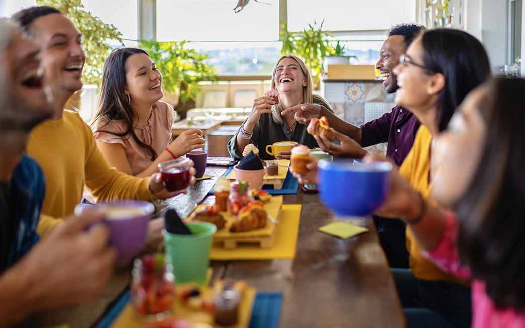 Group of friends enjoying lunch together at a table with drinks and pastries.