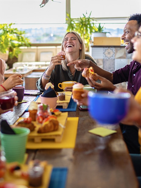 Group of friends enjoying lunch together at a table with drinks and pastries.
