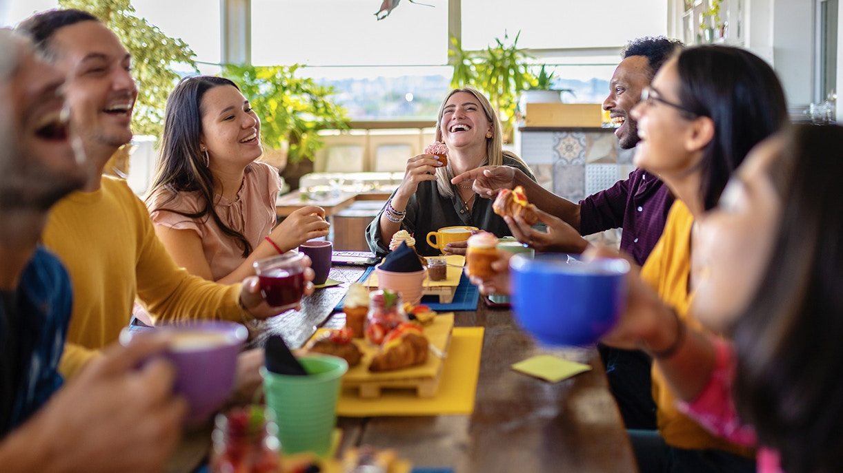 Group of friends enjoying lunch together at a table with drinks and pastries.