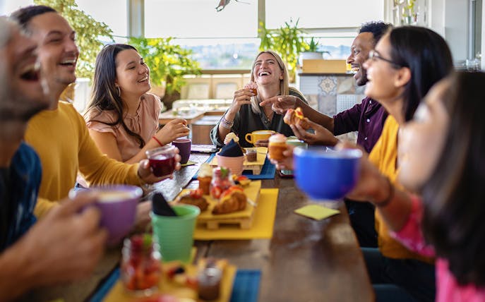 Group of friends enjoying lunch together at a table with drinks and pastries.