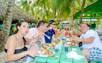 Guests enjoying seafood at a picnic table on Saona Island beach.