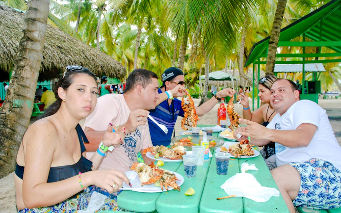 Guests enjoying seafood at a picnic table on Saona Island beach.