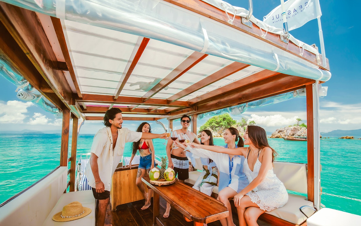 People enjoying a luxury longtail boat cruise in Krabi, toasting with drinks.