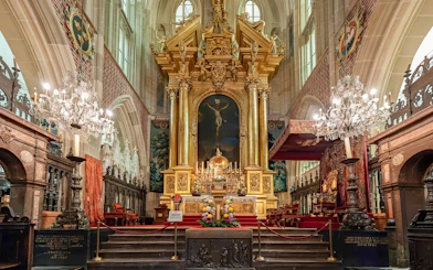 Altar inside Wawel Cathedral, Krakow, Poland with ornate gold detailing and chandeliers.