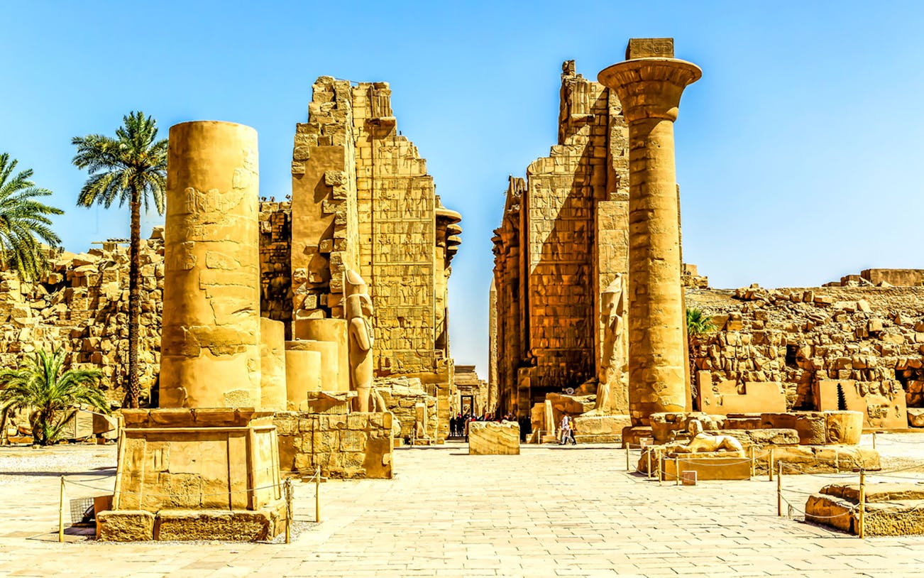 Karnak Temple ruins in Luxor, Egypt, with ancient columns and statues.