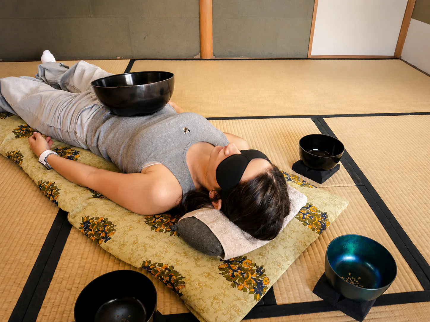 Person experiencing a Japanese sound bath with singing bowls in a Kyoto tatami room.