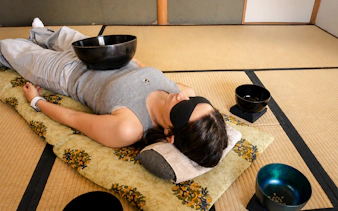 Person experiencing a Japanese sound bath with singing bowls in a Kyoto tatami room.