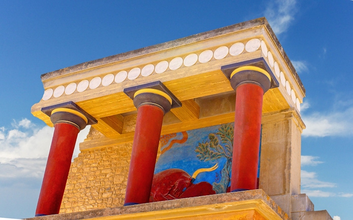 Knossos Palace fresco and red columns under blue sky, Crete, Greece.