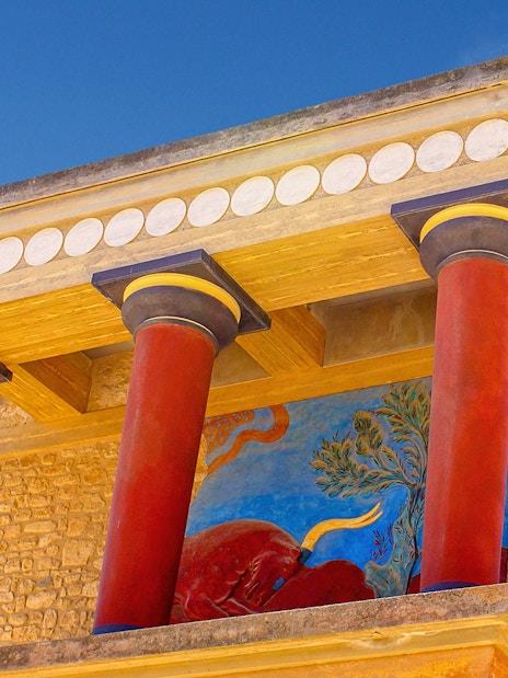 Knossos Palace fresco and red columns under blue sky, Crete, Greece.