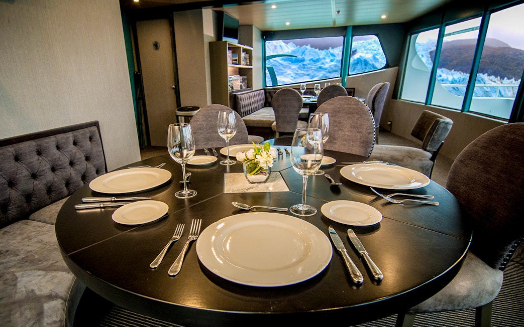 Luxurious dining setup inside a boat with glacier views during Perito Moreno, Spegazzini & Upsala tour.