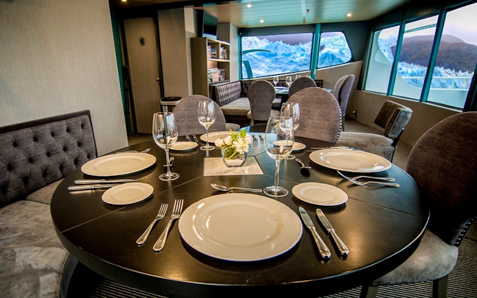 Luxurious dining setup inside a boat with glacier views during Perito Moreno, Spegazzini & Upsala tour.