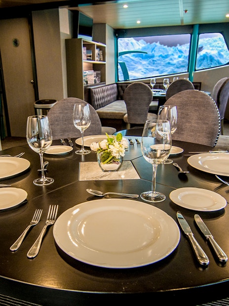 Luxurious dining setup inside a boat with glacier views during Perito Moreno, Spegazzini & Upsala tour.