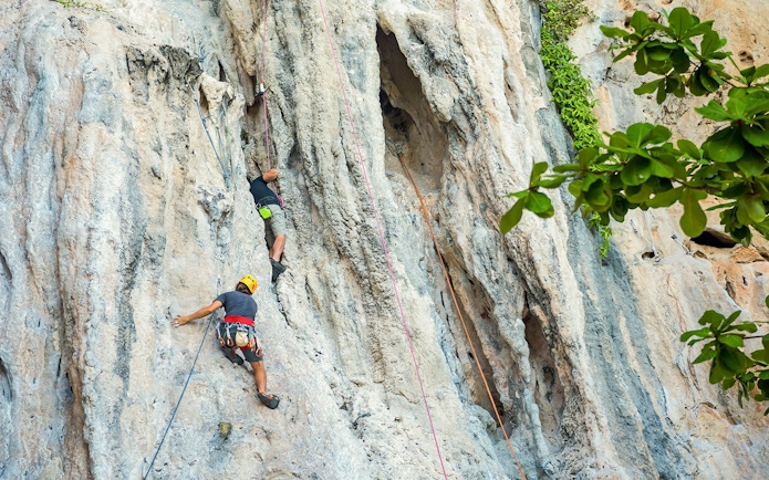 Rock climbers scaling limestone cliffs at Railay Beach, Krabi during a climbing course.