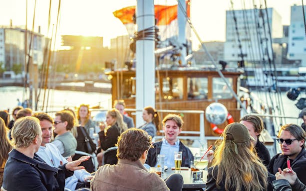 People enjoying drinks on a boat during an Amsterdam Skyline Tour.
