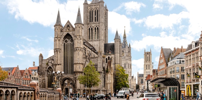 Street scene in Ghent, Belgium, with Saint Nicholas Church and bustling activity.