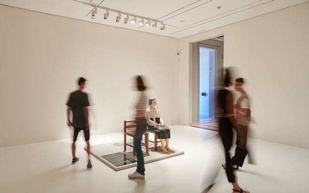 Visitors viewing a seated sculpture at the Museum of Forbidden Art.