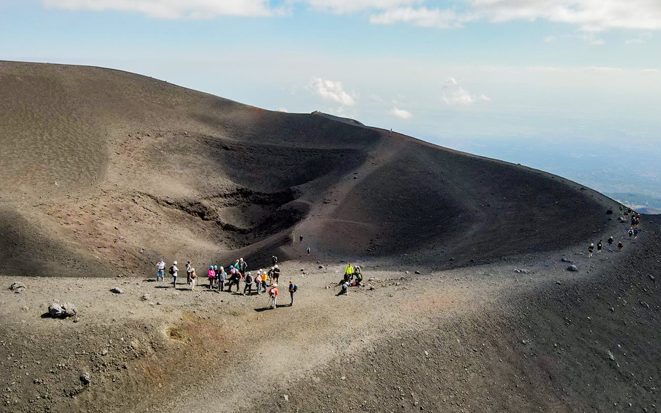 Group hiking on Mount Etna's volcanic landscape during a guided tour from Catania.
