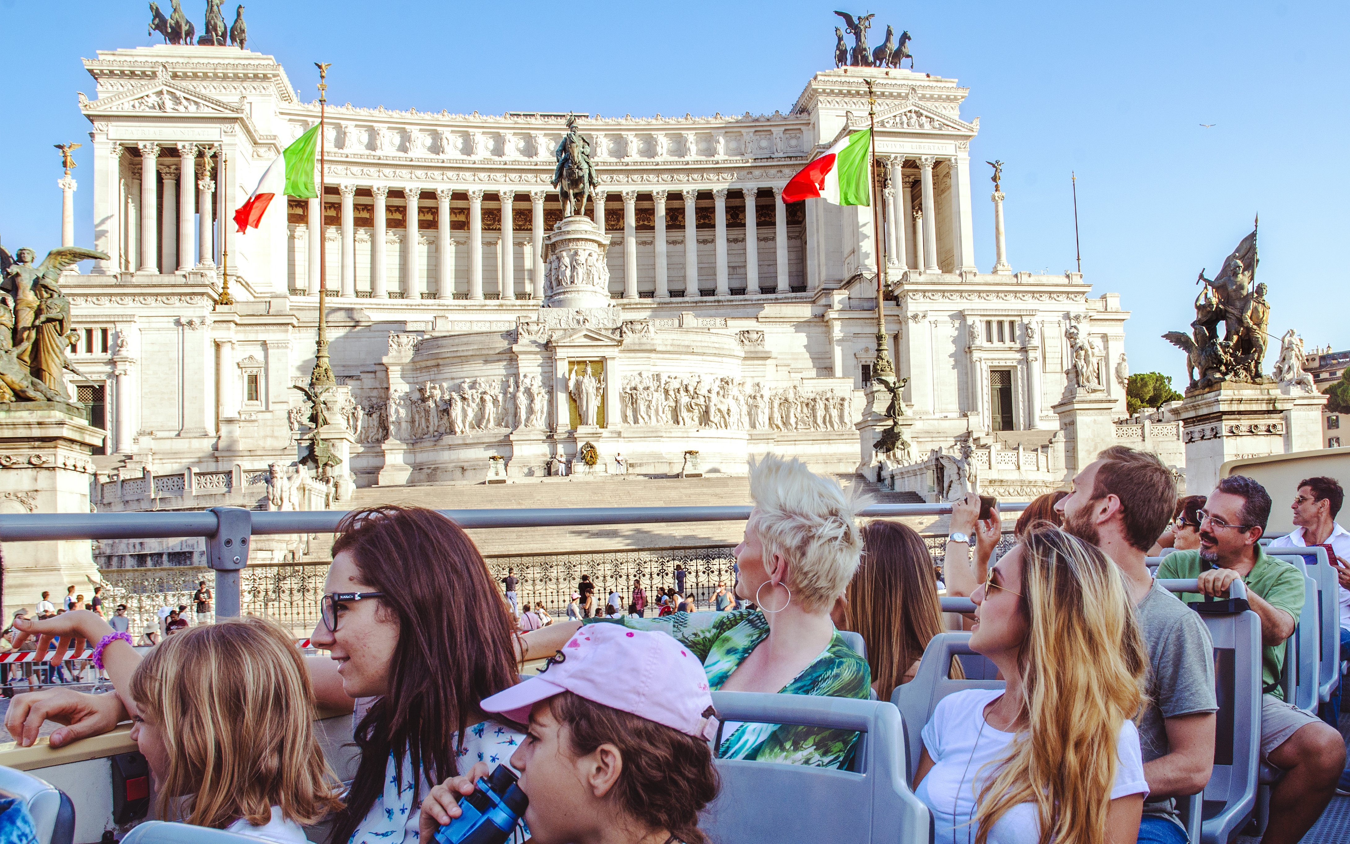 Tourists on a HOHO bus tour viewing the Altare della Patria in Rome.