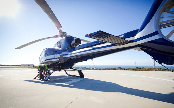 Helicopter on helipad with crew preparing for shared panoramic tour.