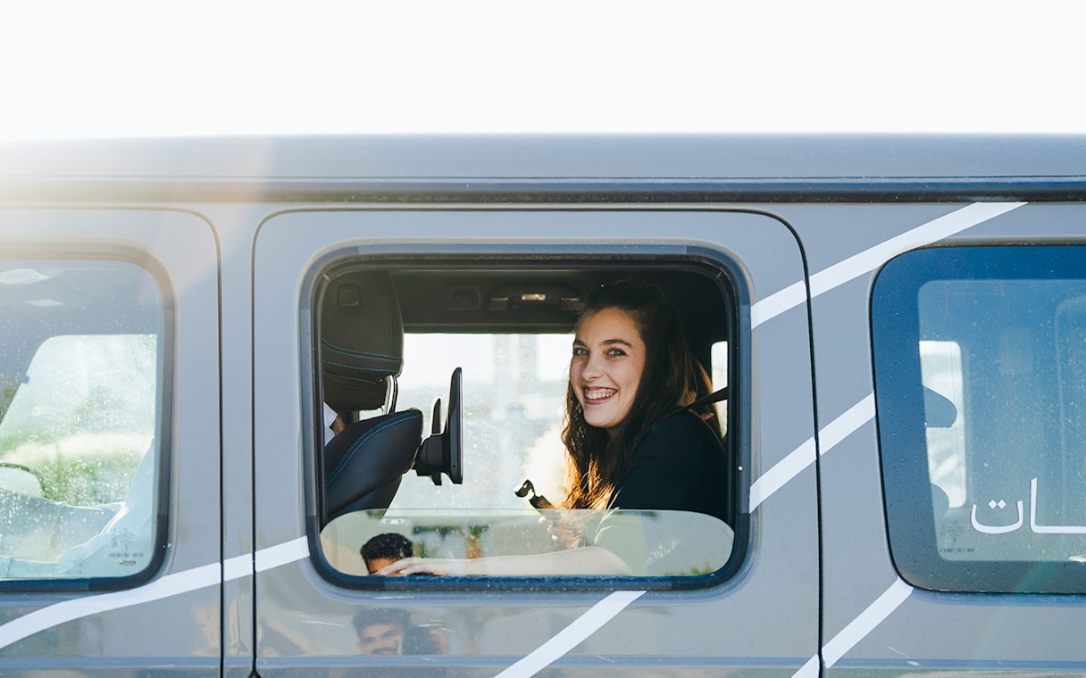 Tourist smiling inside a Mercedes-Benz during Dubai experience tour.