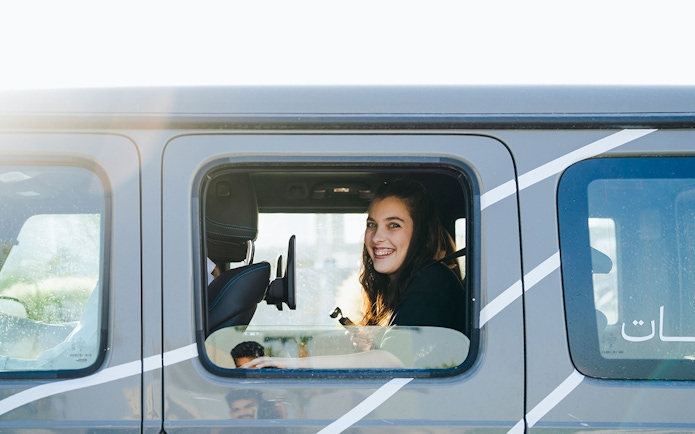 Tourist smiling inside a Mercedes-Benz during Dubai experience tour.