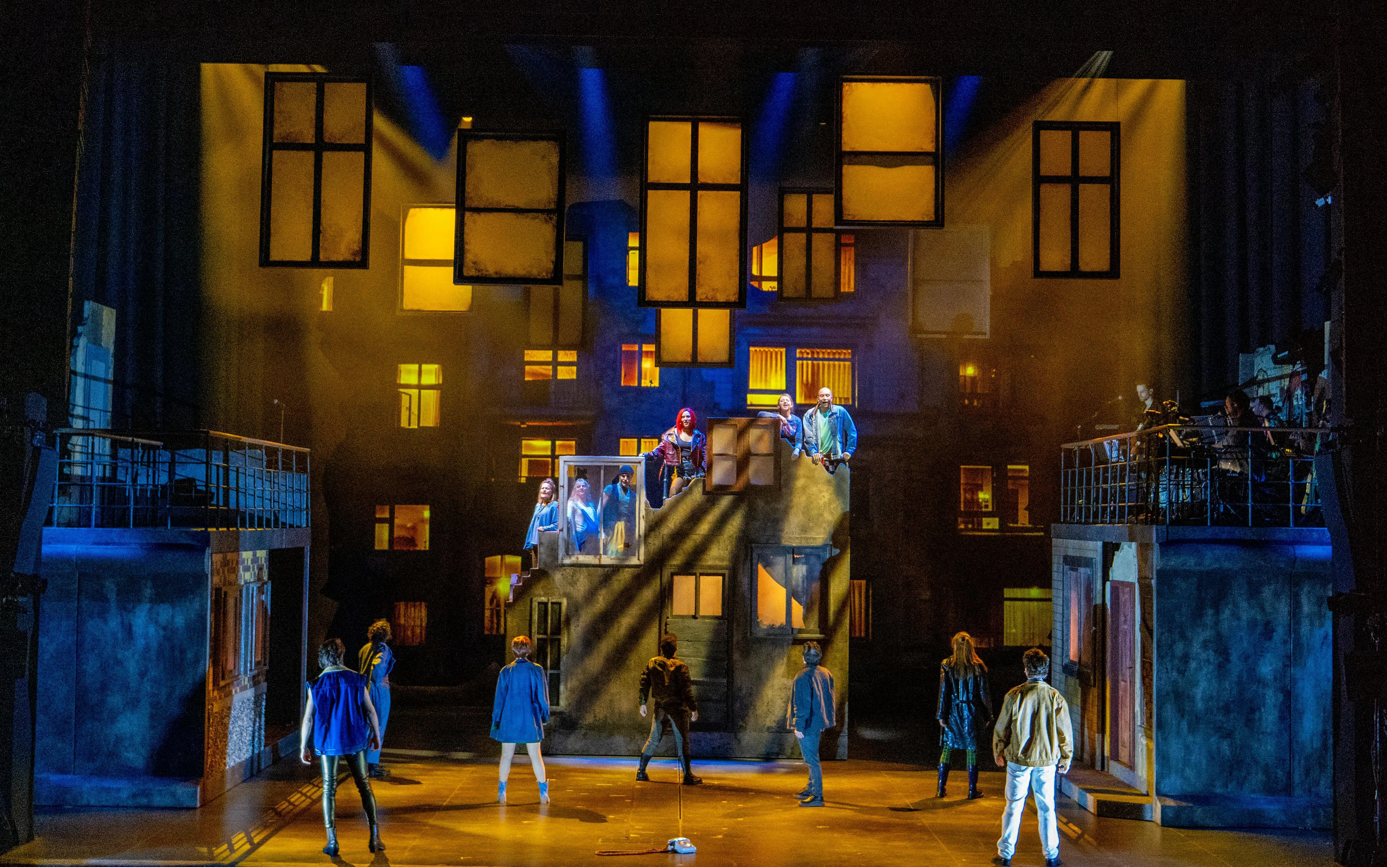 Stage performance of "We Are Alive" in Berlin with actors on a set resembling urban buildings.